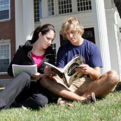 Two students sitting on a lawn