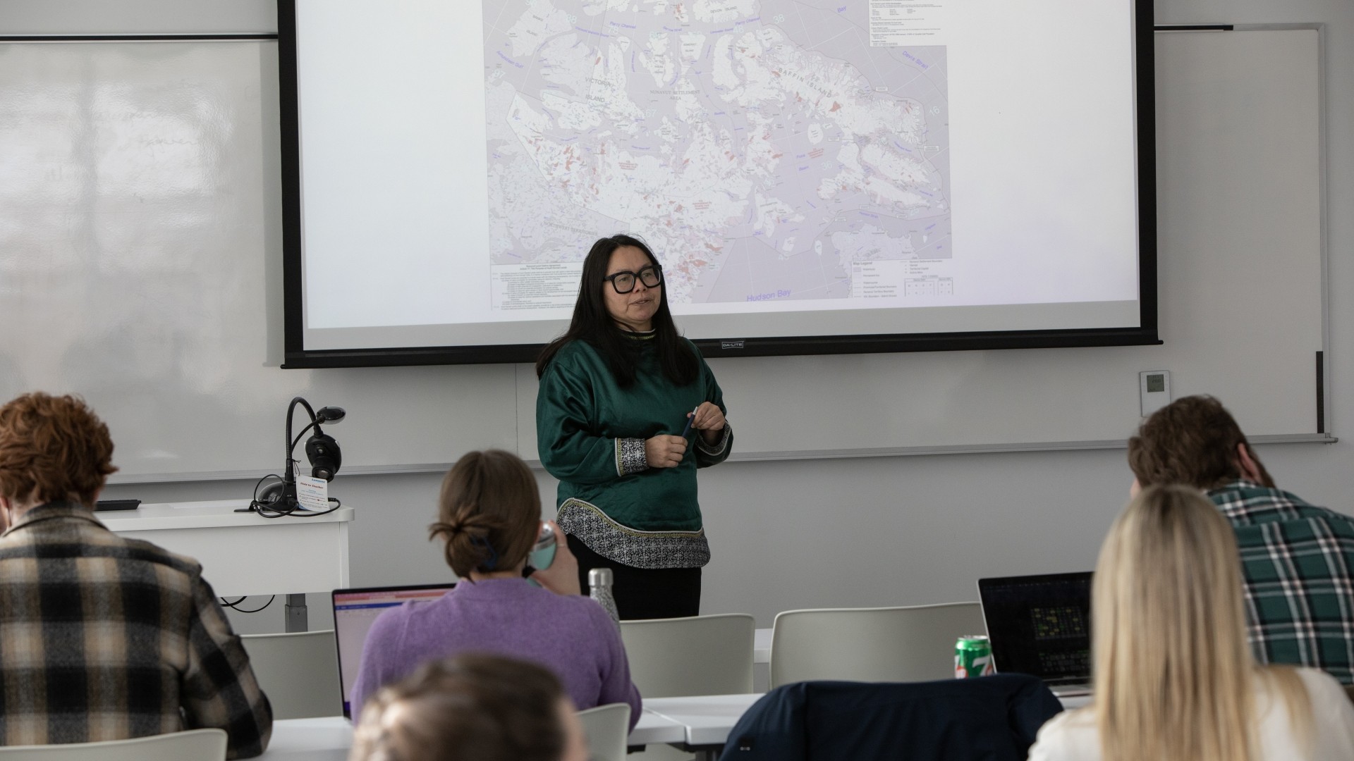A woman presenting to a class in front of a projector screen