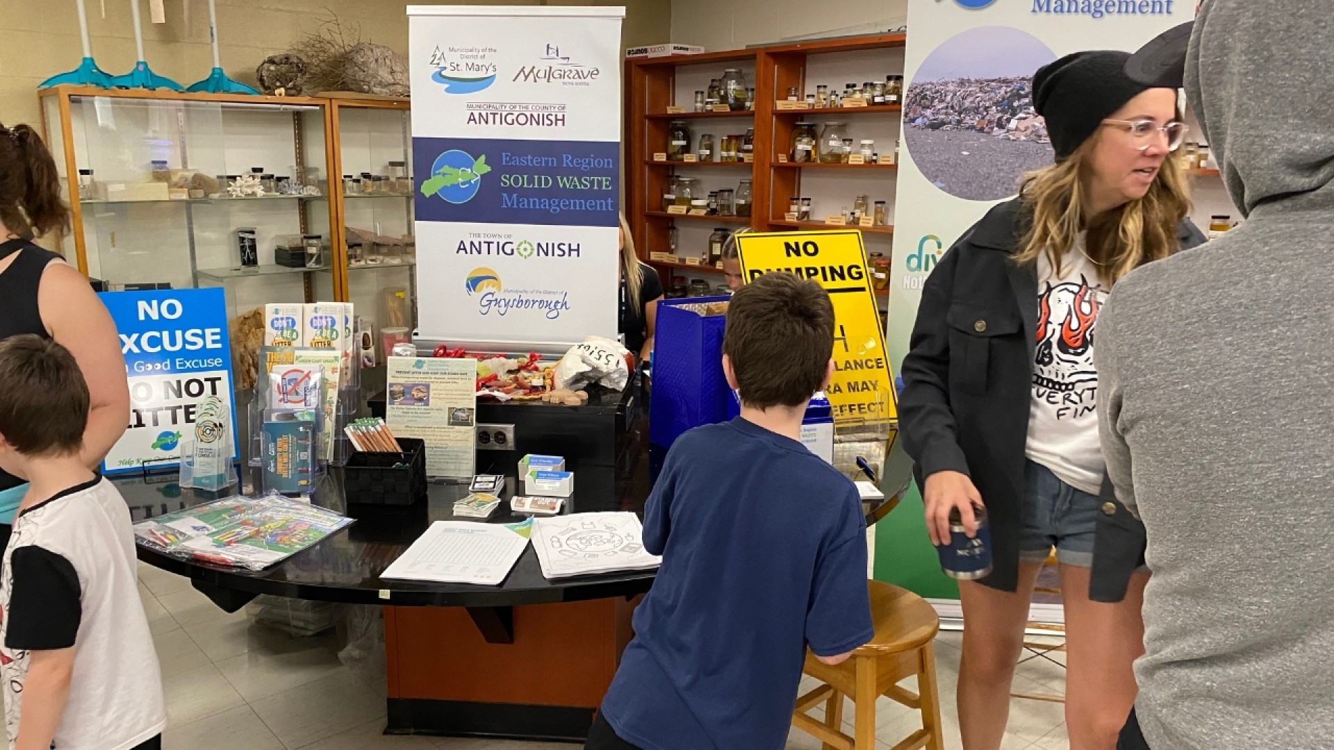 People at an indoor event table with banners and materials about Eastern Region Solid Waste Management.
