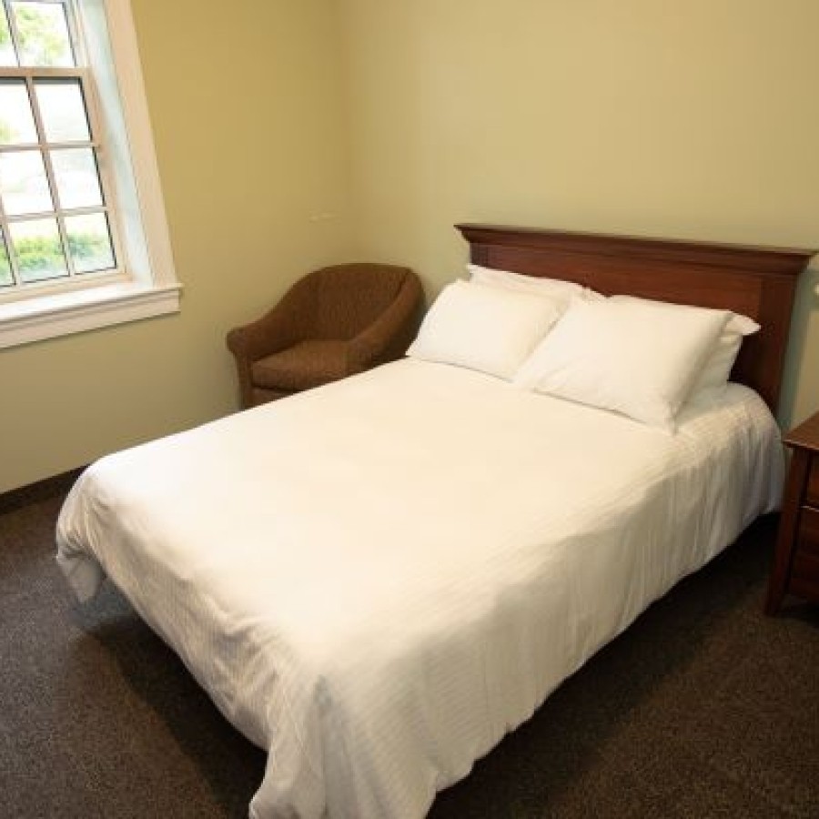 Queen room with bed, bedside table and small couch