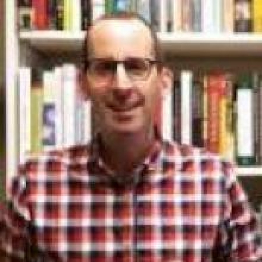 A person in front of a bookcase smiling