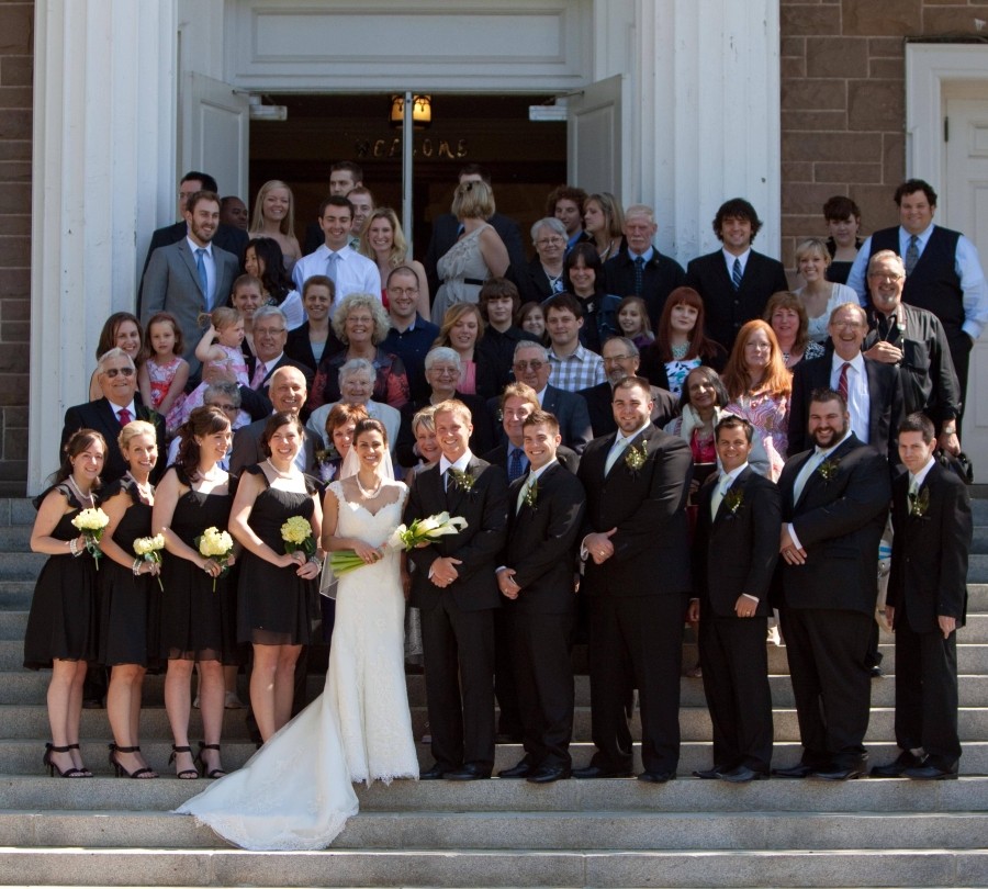 A large group of people including a wedding party on church steps