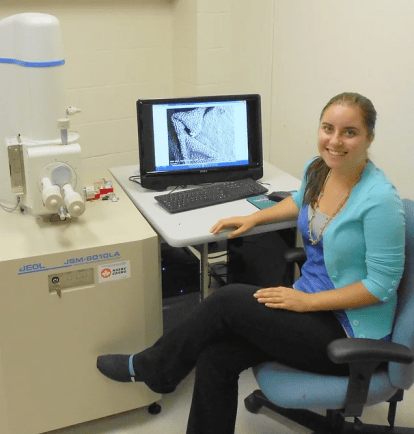 A student at a desk with a computer and microscope