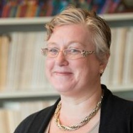 A person in front of a bookcase smiling